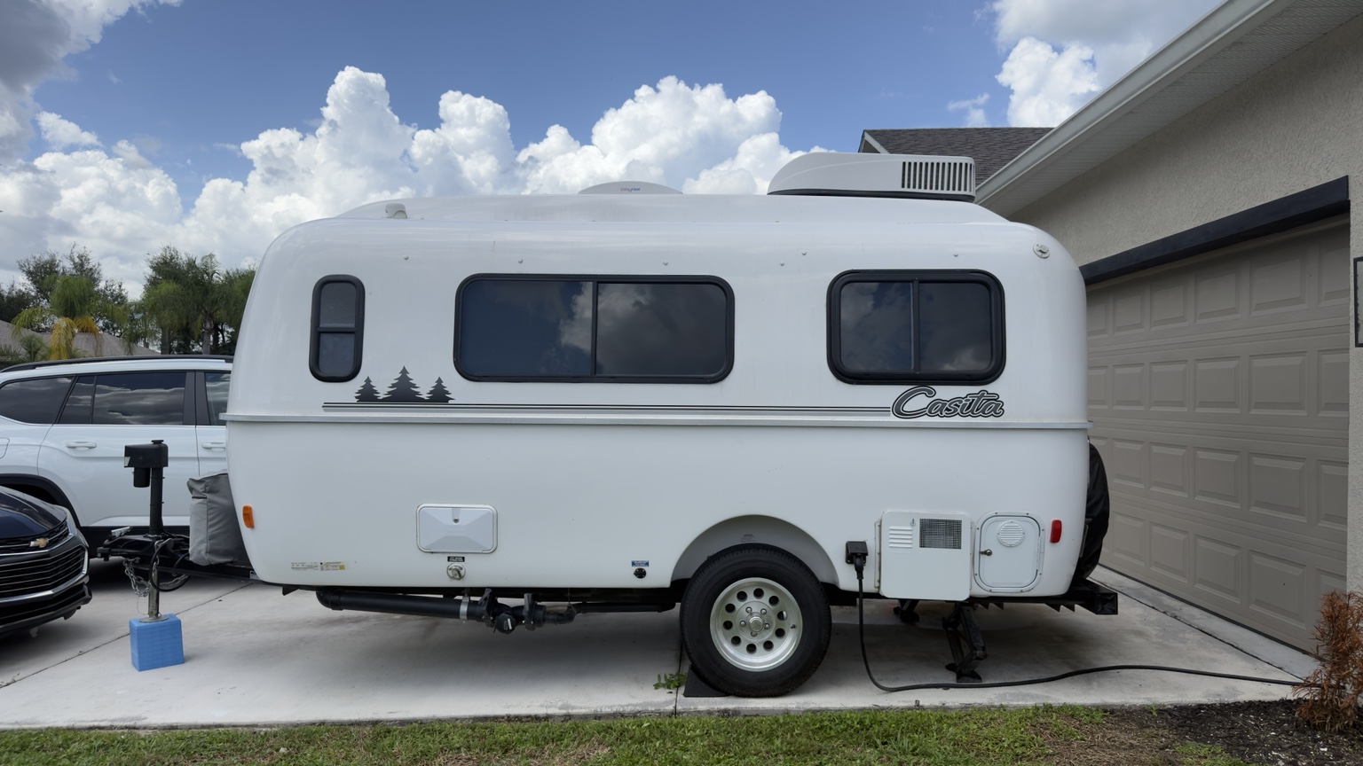 White Casita travel trailer with tinted windows parked in a driveway